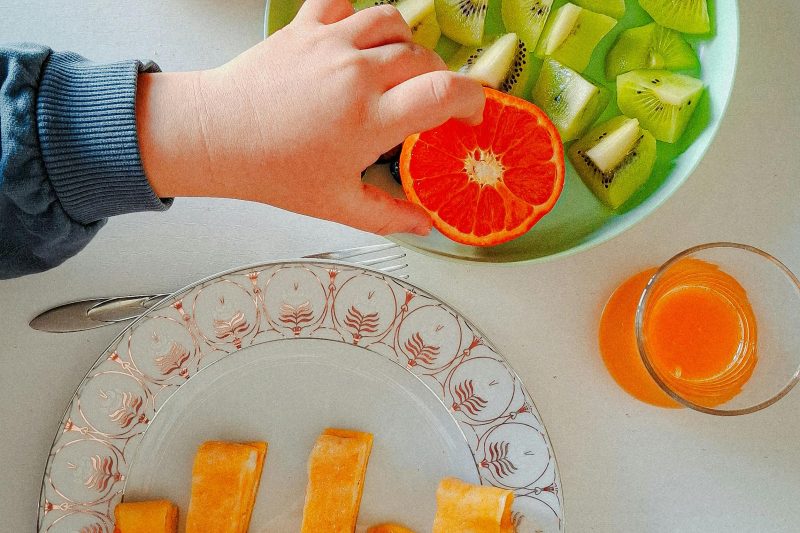 toddler picking some fruits from a plate